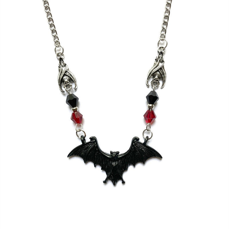 Necklace with a black bat pendant and red beads on a white background