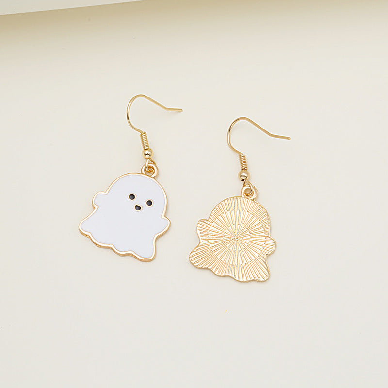 Ghost-shaped earrings with gold and white designs on a light beige background