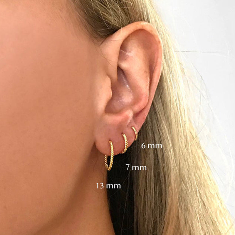 Gold hoop earrings displayed on an ear with size labels.