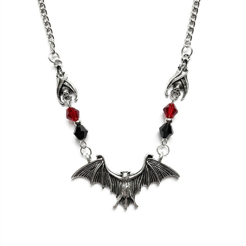 Necklace with bat pendant and red beads on a white background