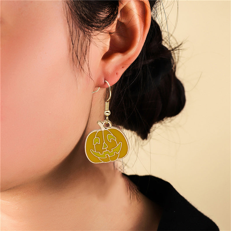 Close-up of a lady wearing a pumpkin-shaped earring against a beige background