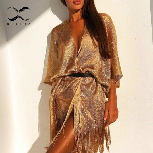 Woman wearing a gold fringe dress with BIKINX logo in the corner.
