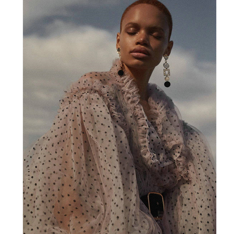 Woman wearing a sheer polka dot dress  or cover up with a blurred sky background